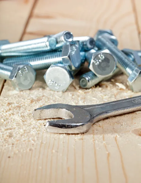 Tornillos y llave en superficie de madera — Foto de Stock