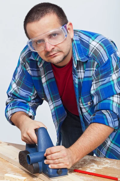 Hombre trabajando madera con una cepilladora eléctrica — Foto de Stock