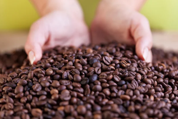 Woman grabbing a handful of roasted coffee beans — Stock Photo, Image