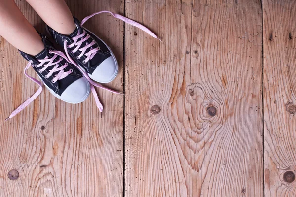 Dětské nohy v sneekers na staré dřevěné podlahy — Stock fotografie