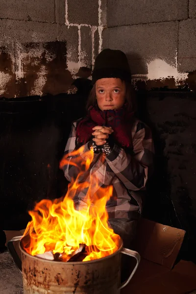 Szegény koldus gyermek bemelegítés a tűz egy bádog edényben — Stock Fotó