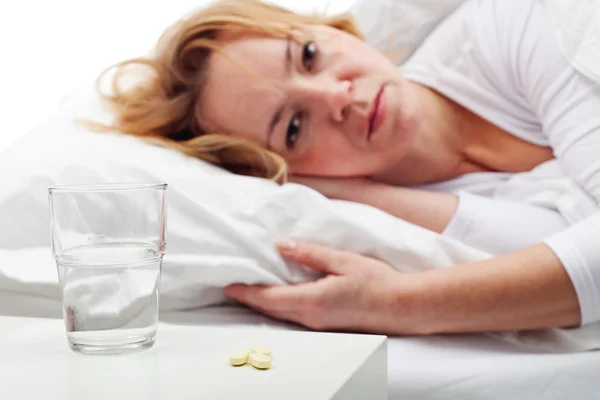 Tabletten einnehmen - Frau liegt im Bett — Stockfoto