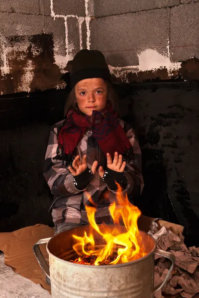 Young homeless boy on the street warming his hands — Stock Photo, Image