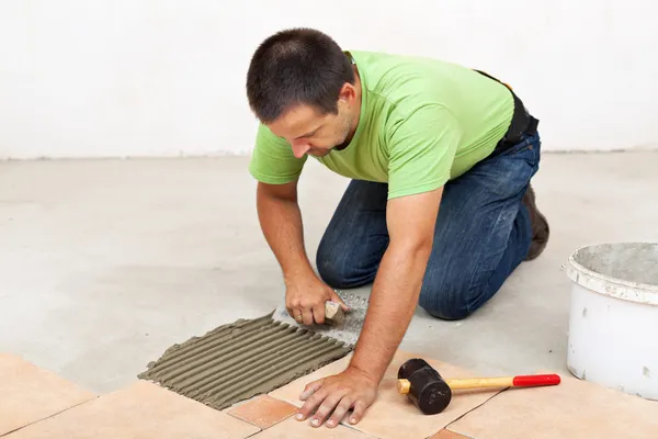 Man laying floor tiles - spreading the adhesive — Stock Photo, Image