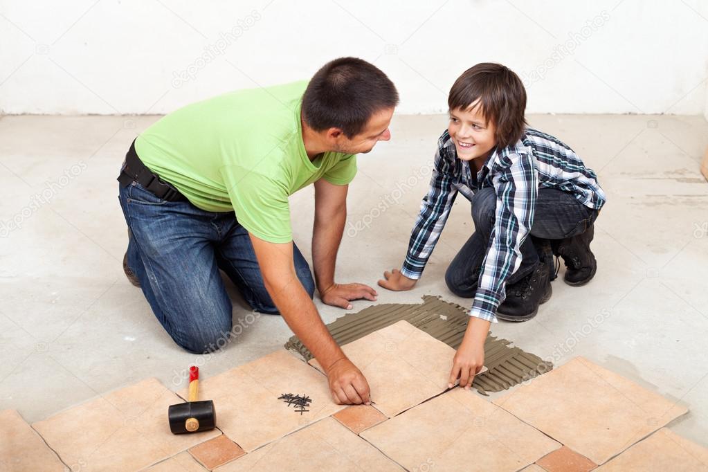 Father and son laying ceramic floor tiles