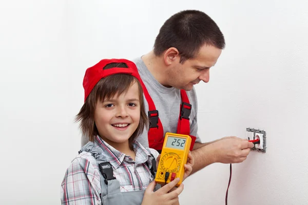 Glücklicher Junge hilft seinem Vater bei der Montage elektrischer Wandbefestigungen — Stockfoto