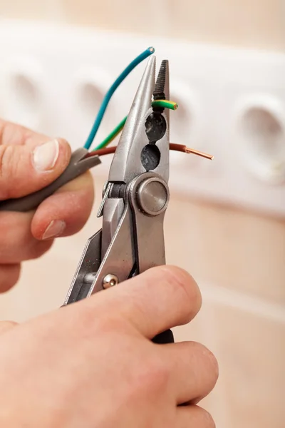 Manos de electricista con alicates y cables — Foto de Stock