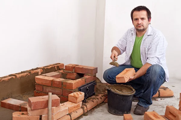 Man building a brick stove or fireplace — Stock Photo, Image