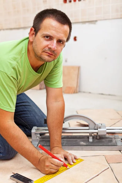 Man marking and cutting ceramic floor tiles — Stock Photo, Image