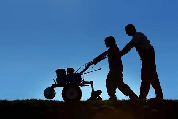 Pai e filho trabalhando a terra com um lavrador — Fotografia de Stock