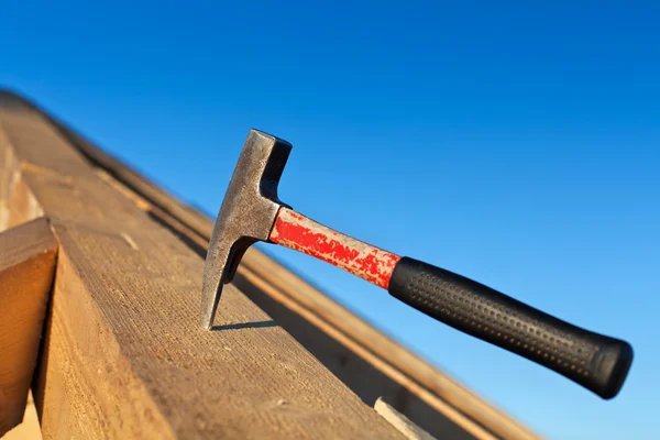 Carpenter hammer stuck into a wooden beam — Stock Photo, Image