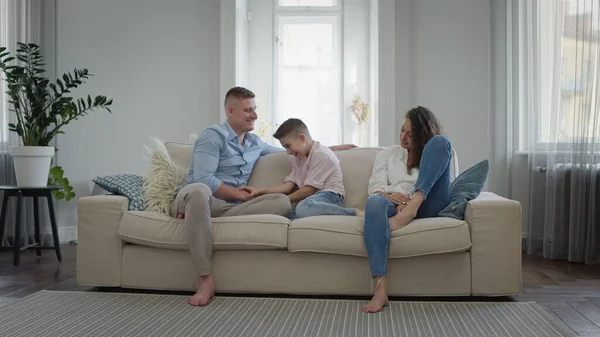 En lykkelig ung familie på sofaen i leiligheten. Pappa Mamma og sønn ler og har det gøy. – stockfoto