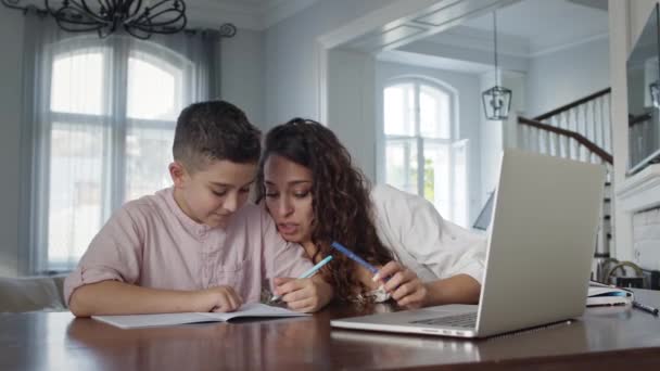 Young Mother And Son At The Table. Boy Writes In Notebook. He Does His Homework. — Stock Video