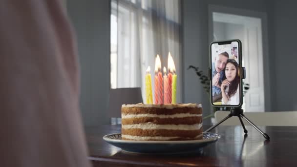 Ragazzo seduto davanti alla torta a tavola. Sul Tavolo Telefono. Al telefono Giovani mamma e papà si congratulano con il loro figlio per il suo compleanno. — Video Stock