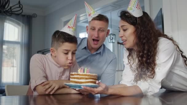 아버지와 아들은 아들의 생일을 기념 한다. 엄마가 케이크를 만들고 아들이 촛불을 끄다. — 비디오