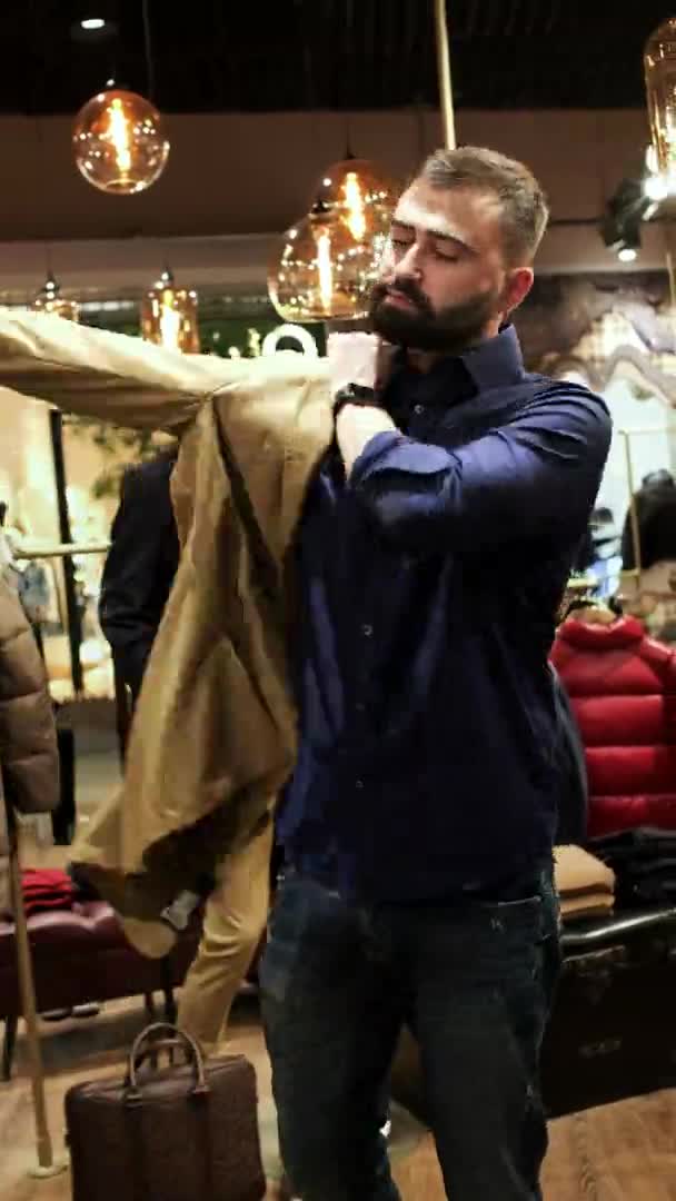 Mağazada ceket deneyen genç adam. Süslü kahverengi ceket giyiyor.. — Stok video