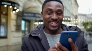 Genç siyahi adam elinde telefonla caddede yürüyor. Telefonu sanki biriyle mektuplaşıyormuş gibi kullanıyor..
