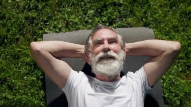 Mat 'te Çimlerde Yatan Yaşlı Adam. Gökyüzüne bakıyor. Sakallı Gri Adam. Pozitif Gülümseyen Adam.