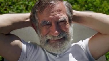 Mat 'te Çimlerde Yatan Yaşlı Adam. Elleri boynunda. Egzersiz yapıyor. Sakallı Gri Adam.