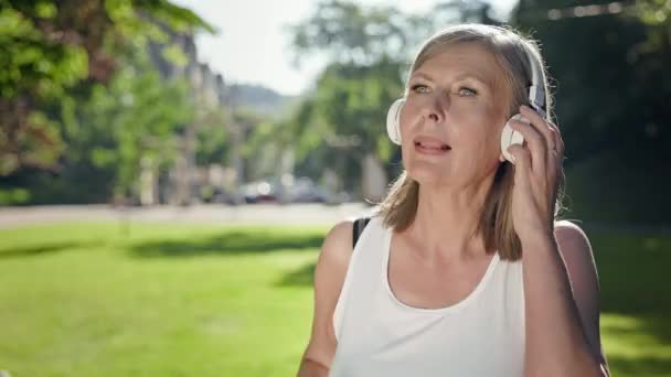 Grå Kvinna Parken Lyssnar Musik Hörlurar Hennes Händer Telefonen Hon — Stockvideo