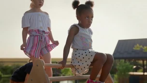 儿童在游乐场 黑妞从木片上下来了三个可爱的孩子 黑人女孩先来的滑梯 在她的白人女孩和男孩后面 — 图库视频影像