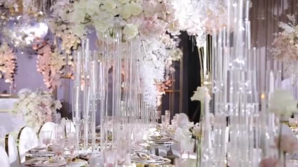 レストランで絶妙なお祭りテーブル テーブルは花で飾られ 提供されています 光の色で 特別なイベントのためのレストランで絶妙な料理 白とピンクの色合いのバラの多く — ストック動画
