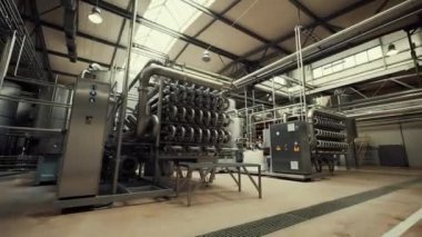 Juice Prodüksiyon Ekipmanı. Modern Fabrika. Otomatik Pompalama İstasyonu çalışan sıvıyı borulardan pompalıyor. Ekipman yüksek kaliteli paslanmaz çelikten yapılmıştır. Endüstriyel Lambalar Aydınlat