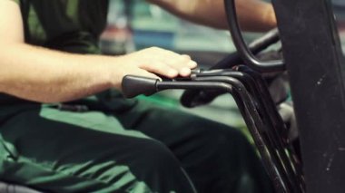 Yakın plan. Forklift üzerinde çalışan bir adam. Sürücü, makinedeki manivelayı değiştiriyor..
