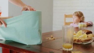 Annem bir kağıt havluyu yırttı. Annem masadaki kırıntıları kağıt peçeteyle temizliyor..
