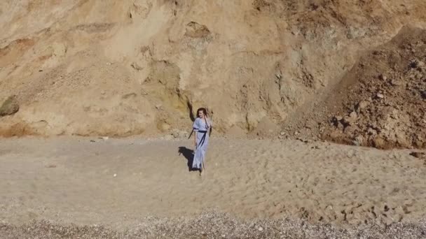 空中景观 美丽的年轻女子在海滩上散步 迷人的女孩赤脚在沙滩上散步 模特身上穿着长长的 轻盈的 自由的衣服 — 图库视频影像