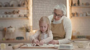 Noel tatilleri. Büyükannem ve küçük kızım mutfakta. Arkalarında teçhizatlı bir sürü raf var. Kız, farklı şekillerde hamur şekline bürünüyor. Noel kurabiyesi yapıyorlar. Büyükanne Servis