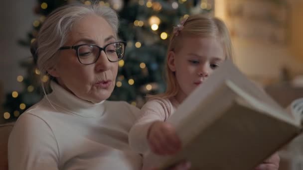 Újévi Ünnepek Nagyi Unokakönyvet Olvassa Együtt Ülnek Kanapén Szürke Szemüvegben — Stock videók