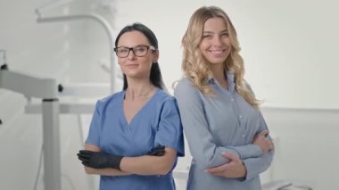 Genç dişçi ve dişçi muayenehanesindeki kız müşteri. Ayağa kalkıp gülümsüyorlar. Uzun siyah saçlı gözlüklü doktor. Müşteri Sarışın Kız.