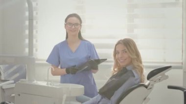 Ofiste çalışan dişçi. Sandalyedeki genç sarışın. Dişçide resepsiyon. Genç bir hastanın yüzünü kapatın. Çekici Gülümseyen Sarışın Kız. Kadın Doktor Kadın Hastanın Yanında Duruyor.