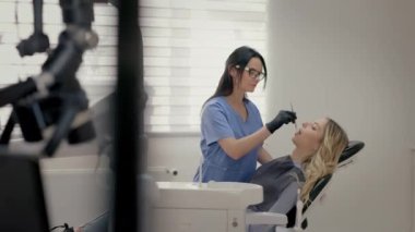 Ofiste çalışan dişçi. Sandalyedeki genç sarışın. Dişçide resepsiyon. Çekici Gülümseyen Sarışın Kız. Doktor, Ayna ile hastaların ağzını muayene eder. Gözlüklü genç bayan doktor..