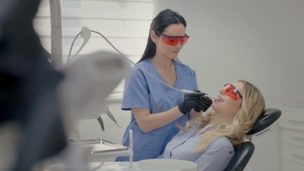 歯医者で働いている 機材を持って走る若い女性 ヤング ブロンド議長 歯医者での受付 若い患者の顔を閉じる 魅力的な笑顔のブロンドの女の子 — ストック動画