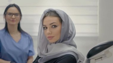 Ofiste çalışan dişçi. Yakındaki genç hastanın yüzü. Kafasında atkısı olan genç kız Dişçi koltuğunda oturuyor..