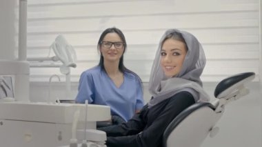 Ofiste çalışan dişçi. Yakındaki genç hastanın yüzü. Kafasında atkısı olan genç kız Dişçi koltuğunda oturuyor..