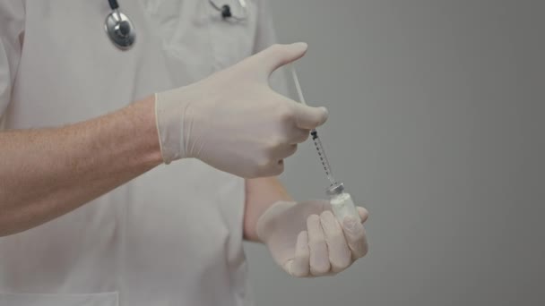 医師の手薬でシリンジを埋める 彼は注入する準備をしている 注射器から薬瓶に液体を空にする — ストック動画