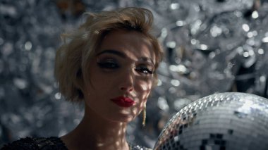 Akşamki Şenlik Kostümünde Baştan Çıkarıcı Sarışın Eriyor. Parlak Kız Sahnesi 'nin arkasında. Parlak Makyaj ve Büyük Küpeli Adorn Kız.