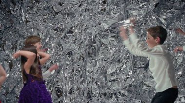 Gümüş Sahne Arkaplanındaki Beş Çocuk. Kutlama. Üç Oğlan ve İki Kız. Neşeli Çocuklar. Beyaz tişörtlü erkekler ve elbiseli kızlar..