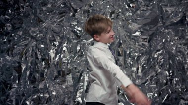 Parlak Sahne 'nin Arkasında Dans Eden Neşeli Çocuk. Yeni Yıl Kutlaması. Beyaz tişörtlü ve kravatlı çocuk..