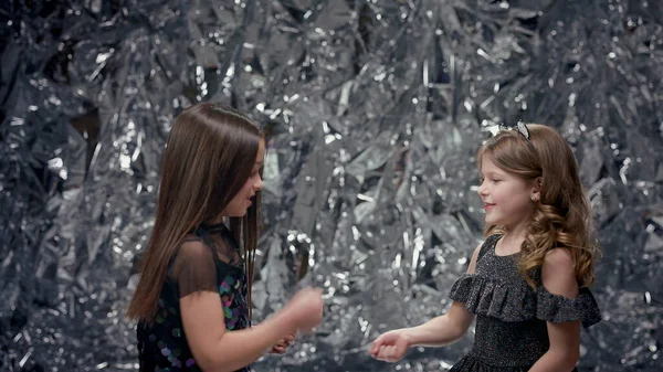 Parlak Arkaplanda İki Kız. Şenlik Elbiseli Kızlar. Kızlar gülümsüyor. Çocuklar eğlensin. Oyun oynarlar ve farklı el hareketleri yaparlar..