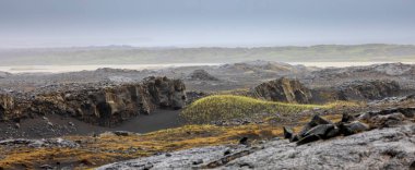 Panoramic view of volcanic black sand and rocky terrain in western Iceland