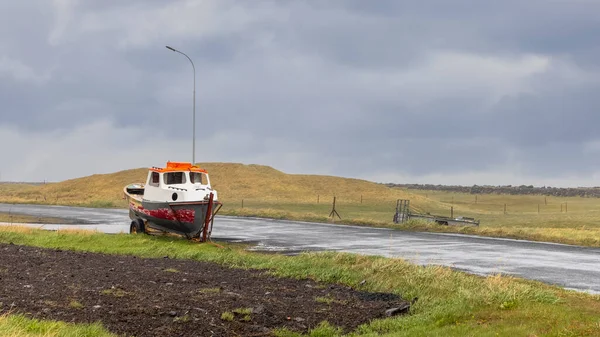 在多云的天空和雨天下 冰岛农村拖车上的老渔船 — 图库照片