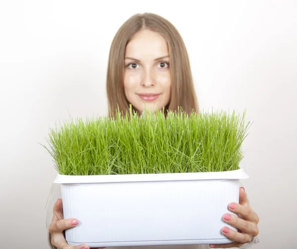 Kvinna med kruka med grönt gräs — Stockfoto