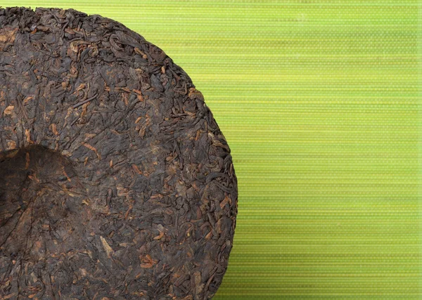 Scheibe Puer Tea auf grünem Hintergrund — Stockfoto
