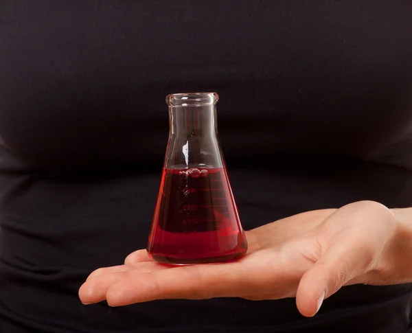 Hand mit Chemieflasche auf schwarzem Hintergrund — Stockfoto
