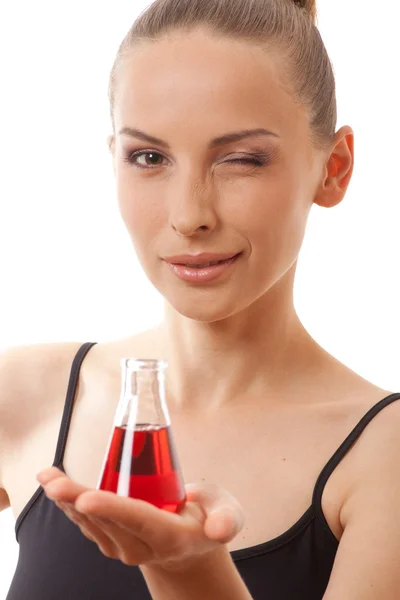 Femme en costume de sport tient fiole avec liquide rouge — Photo