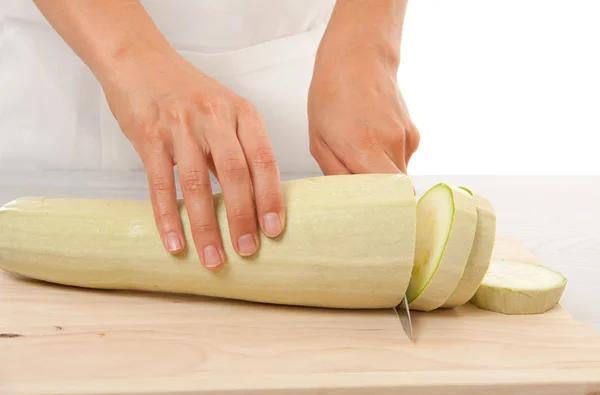 Female chef cut one zucchini with a kitchen knife — Stock Photo, Image